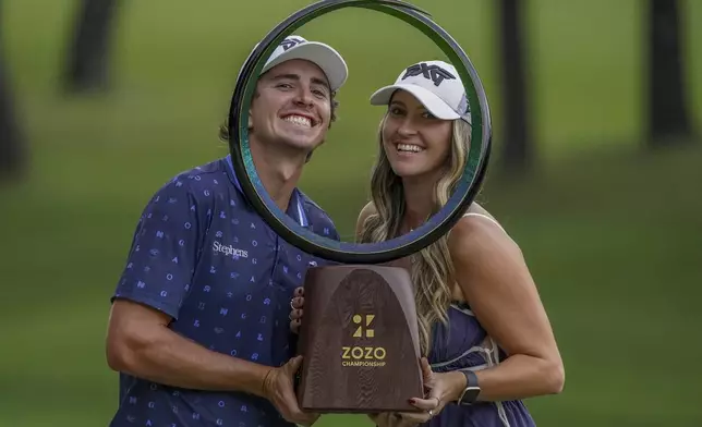 Nico Echavarria of Colombia, left, along with his girlfriend, poses with the trophy after winning the PGA Tour Zozo Championship at the Narashino Country Club in Inzai on the outskirts of Tokyo, Sunday, Oct. 27, 2024. (AP Photo/Tomohiro Ohsumi)