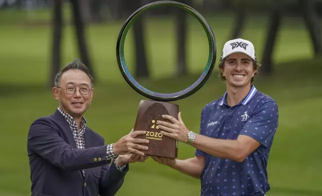 Nico Echavarria of Colombia, right, is presented the trophy by Zozo President and CEO Kotaro Sawada after winning the PGA Tour Zozo Championship at the Narashino Country Club in Inzai on the outskirts of Tokyo, Sunday, Oct. 27, 2024. (AP Photo/Tomohiro Ohsumi)