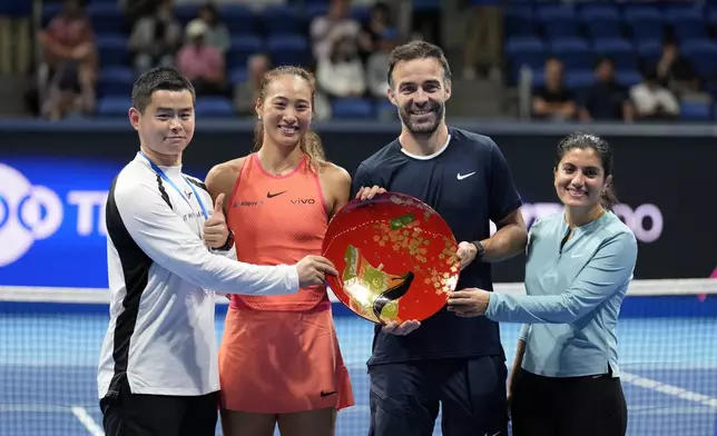 China's Zheng Qinwen and her supporting team pose with the trophy after she won the Pan Pacific Open women's tennis tournament at Ariake Coliseum, in Tokyo, Sunday, Oct. 27, 2024. (AP Photo/Eugene Hoshiko)