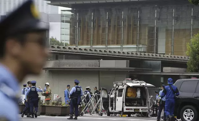 Police officers work near a vehicle, center, which was stuck against a barricade near the prime minister's office, background, in Tokyo Saturday, Oct. 19, 2024. (Kyodo News via AP)