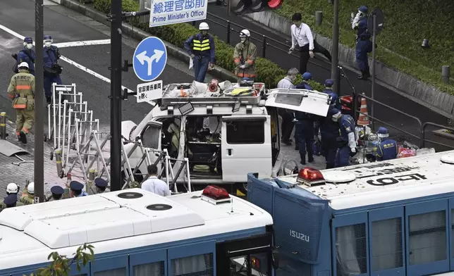 Officials work near a vehicle, center, which was stuck against a barricade near the prime minister's office in Tokyo Saturday, Oct. 19, 2024. (Kyodo News via AP)