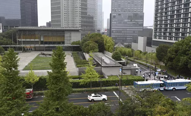 Officials work near a white vehicle, right above, which was stuck against a barricade near the prime minister's office in Tokyo Saturday, Oct. 19, 2024. (Kyodo News via AP)