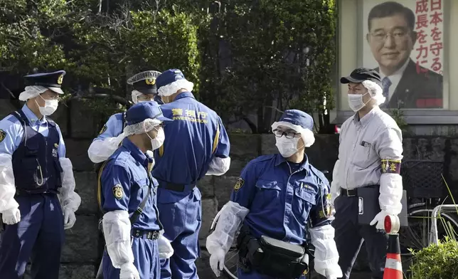 Police officers gather near the headquarters of Japan's ruling Liberal Democratic Party with a poster of Japan's Prime Minister and the party's head Shigeru Ishiba on display after a man threw firebombs into the headquarters in Tokyo Saturday, Oct. 19, 2024. (Kyodo News via AP)