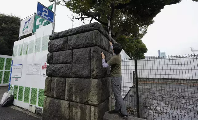 Protest leader Satoru Osawa, tries to take a picture of the demolition work as environmentalists hold a rally near the Jingu Gaien park district of central Tokyo, Japan, where property developer Mitsui Fudosan begins cutting trees as part of the redevelopment of the area, Monday, Oct. 28, 2024. (AP Photo/Hiro Komae)