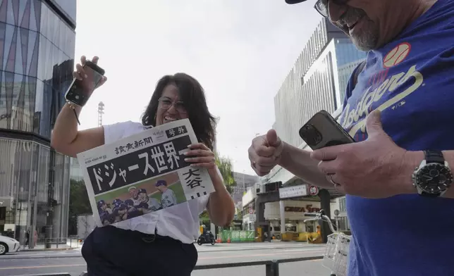 Bystanders receive copies of an extra edition of the Yomiuri Shimbun newspaper in Tokyo, Thursday, Oct. 31, 2024, reporting on the Los Angeles Dodgers' victory in the World Series baseball match against the New York Yankees in Game 5 in New York. The headline of the newspaper said "Dodgers is No. 1 in the World." (AP Photo/Eugene Hoshiko)