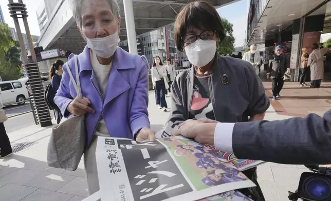 Bystanders receive copies of extra editions of the Yomiuri Shimbun and the Sports Nippon newspapers in Tokyo, Thursday, Oct. 31, 2024, reporting on the Los Angeles Dodgers' victory in the World Series baseball match against the New York Yankees in Game 5 in New York. The headline of the Yomiuri newspaper said "Dodgers is No. 1 in the World." (AP Photo/Eugene Hoshiko)