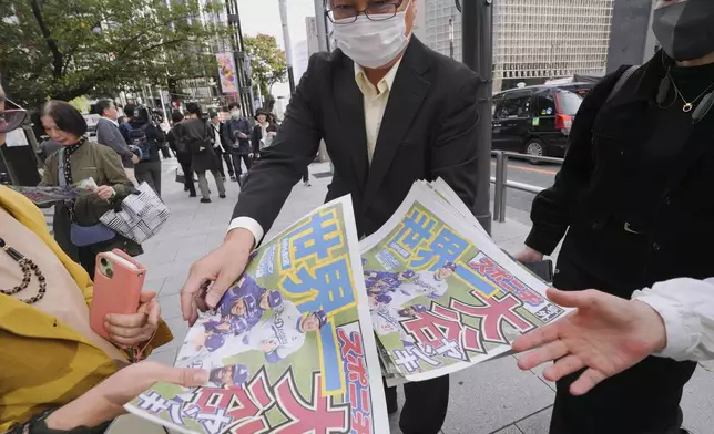 A staff member distributes copies of an extra edition of the Sports Nippon newspaper in Tokyo, Thursday, Oct. 31, 2024, reporting on the Los Angeles Dodgers' victory in the World Series baseball match after the Dodgers defeated the New York Yankees in Game 5 in New York. (AP Photo/Eugene Hoshiko)