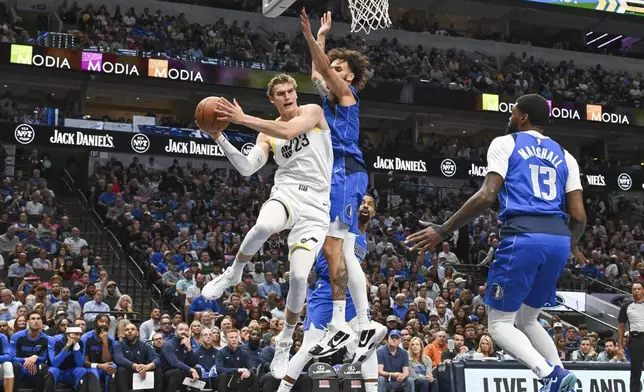 Utah Jazz forward Lauri Markkanen (23) looks to pass the ball as he is defended by Dallas Mavericks forward Dallas Mavericks center Dereck Lively II, center right, and forward Naji Marshall (13) during the first half of an NBA basketball game, Monday, Oct. 28, 2024, in Dallas. (AP Photo/Albert Pena)