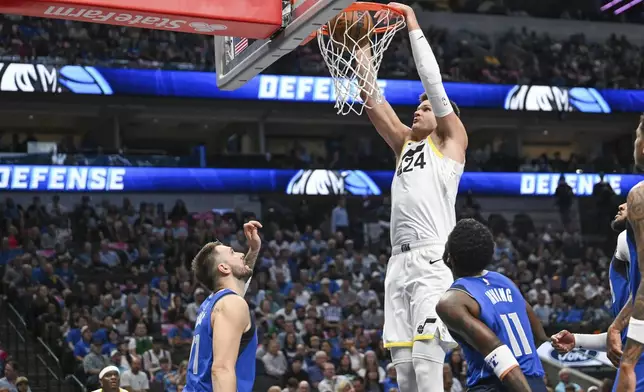 Utah Jazz center Walker Kessler (24) dunks as Dallas Mavericks guards Luka Doncic, left, and Kyrie Irving (11) watch in the first half of an NBA basketball game, Monday, Oct. 28, 2024, in Dallas. (AP Photo/Albert Pena)