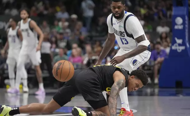 Utah Jazz guard Keyonte George, bottom, falls in front of Dallas Mavericks forward Naji Marshall (13) during the second half of a preseason NBA basketball game Thursday, Oct. 10, 2024, in Dallas. (AP Photo/LM Otero)