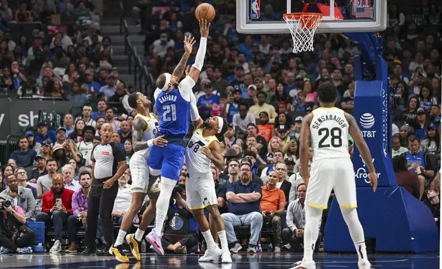 Dallas Mavericks center Daniel Gafford (21) takes a floating jump shot over Utah Jazz forward John Collins, left, and guard Patty Mills (8) during an NBA basketball game, Monday, Oct. 28, 2024, in Dallas. (AP Photo/Albert Pena)