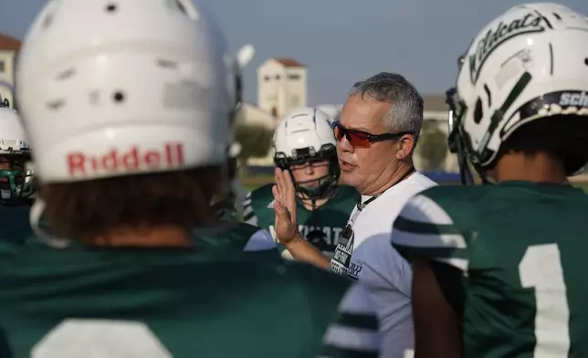 Coach Jim Davis, center, talks to his players during a training session at the football field of the U.S. Naval Support – Site in Gricignano di Aversa, southern Italy, Tuesday, Oct. 29, 2024. (AP Photo/Gregorio Borgia)