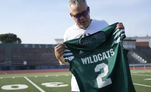 Coach Jim Davis shows the jersey worn by Ashton Jeanty as he is interviewed by The Associated Press prior to the start of a training session at the football field of the U.S. Naval Support – Site in Gricignano di Aversa, southern Italy, Tuesday, Oct. 29, 2024. (AP Photo/Gregorio Borgia)