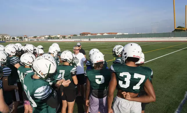 Coach Jim Davis, background center, talks to his players during a training session at the football field of the U.S. Naval Support – Site in Gricignano di Aversa, southern Italy, Tuesday, Oct. 29, 2024. (AP Photo/Gregorio Borgia)