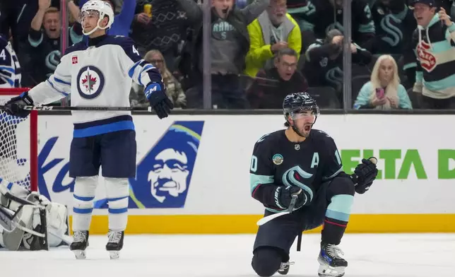 Seattle Kraken center Matty Beniers reacts to scoring as Winnipeg Jets defenseman Neal Pionk, left, looks away during the third period of an NHL hockey game Thursday, Oct. 24, 2024, in Seattle. (AP Photo/Lindsey Wasson)