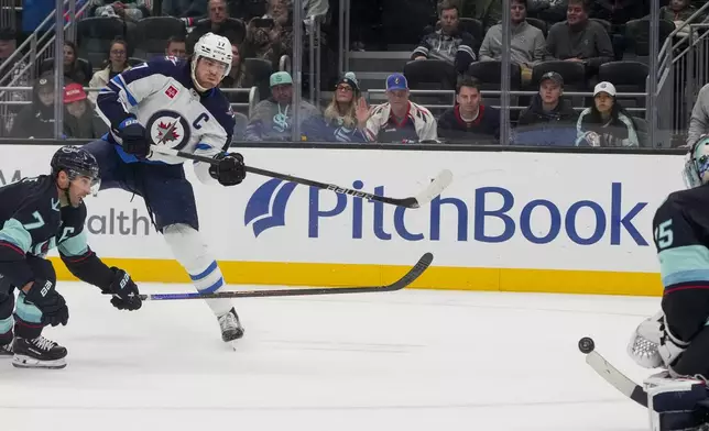 Winnipeg Jets center Adam Lowry (17) shoots as Seattle Kraken right wing Jordan Eberle (7) looks on, but his shot is blocked by goaltender Joey Daccord, right, during the third period of an NHL hockey game Thursday, Oct. 24, 2024, in Seattle. (AP Photo/Lindsey Wasson)