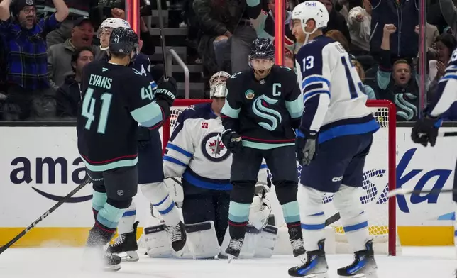 Seattle Kraken right wing Jordan Eberle, center facing, reacts to scoring a goal against Winnipeg Jets goaltender Connor Hellebuyck, back center, during the third period of an NHL hockey game Thursday, Oct. 24, 2024, in Seattle. (AP Photo/Lindsey Wasson)