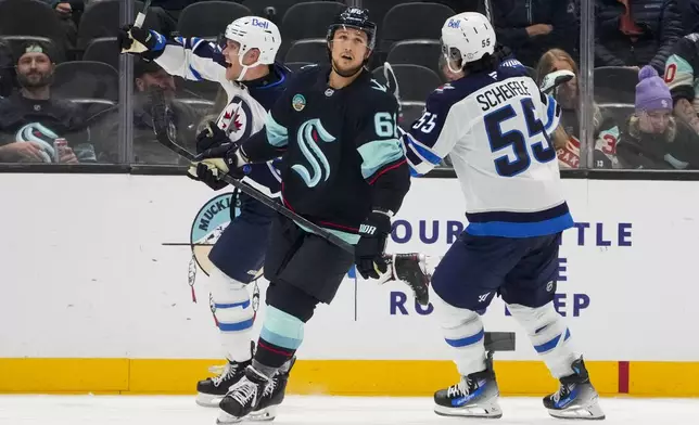 Winnipeg Jets left wing Nikolaj Ehlers, left, celebrates his game-winning goal with center Mark Scheifele (55) as Seattle Kraken defenseman Brandon Montour, center, looks away during overtime of an NHL hockey game Thursday, Oct. 24, 2024, in Seattle. The Jets won 4-3 in overtime. (AP Photo/Lindsey Wasson)