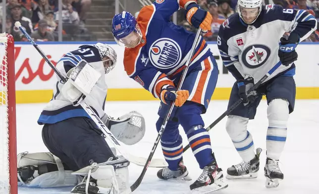 Winnipeg Jets goalie Connor Hellebuyck (37) stops Edmonton Oilers' Corey Perry (90) as Jets' Colin Miller (6) defends during second period NHL action in Edmonton, Alberta, Wednesday, Oct. 9, 2024. (Amber Bracken/The Canadian Press via AP)