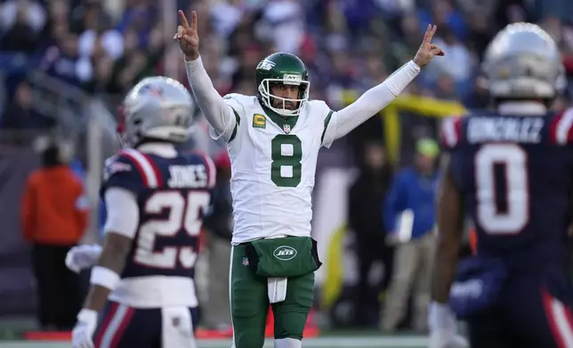 New York Jets quarterback Aaron Rodgers (8) celebrates in front of New England Patriots cornerback Marcus Jones (25) and cornerback Christian Gonzalez (0) after Jets running back Braelon Allen ran for a touchdown in the second half of an NFL football game, Sunday, Oct. 27, 2024, in Foxborough, Mass. (AP Photo/Charles Krupa)