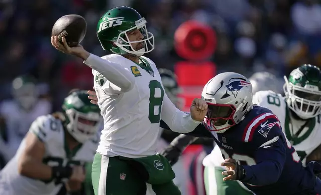 New York Jets quarterback Aaron Rodgers (8) passes under pressure from New England Patriots defensive end Keion White (99) in the second half of an NFL football game, Sunday, Oct. 27, 2024, in Foxborough, Mass. (AP Photo/Charles Krupa)