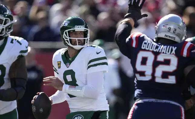 New York Jets quarterback Aaron Rodgers (8) looks for an opening to pass under pressure from New England Patriots defensive tackle Davon Godchaux (92) in the first half of an NFL football game, Sunday, Oct. 27, 2024, in Foxborough, Mass. (AP Photo/Charles Krupa)