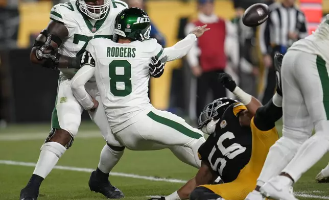 New York Jets quarterback Aaron Rodgers (8) tosses the ball as he is brought down by Pittsburgh Steelers linebacker Alex Highsmith (56) in the first half of an NFL football game in Pittsburgh, Sunday, Oct. 20, 2024. (AP Photo/Gene J. Puskar)