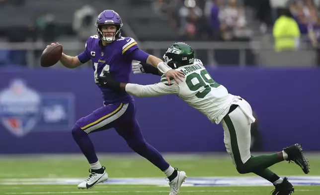 New York Jets' Will McDonald IV, right, sacks Minnesota Vikings quarterback Sam Darnold during the first half of an NFL football game, Sunday, Oct. 6, 2024, at the Tottenham Hotspur stadium in London. (AP Photo/Ian Walton)