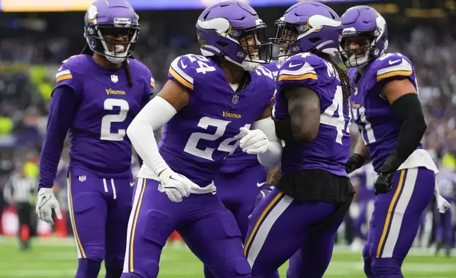 Minnesota Vikings' Camryn Bynum (24), second from left, celebrates an interception with teammates during the first half of an NFL football game against the New York Jets, Sunday, Oct. 6, 2024, at the Tottenham Hotspur stadium in London. (AP Photo/Kirsty Wigglesworth)