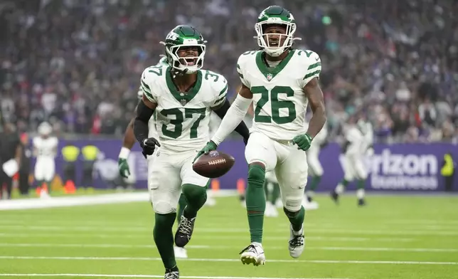 New York Jets' Brandin Echols (26), right, celebrates his interception during the second half of an NFL football game against the Minnesota Vikings, Sunday, Oct. 6, 2024, at the Tottenham Hotspur stadium in London. (AP Photo/Kirsty Wigglesworth)