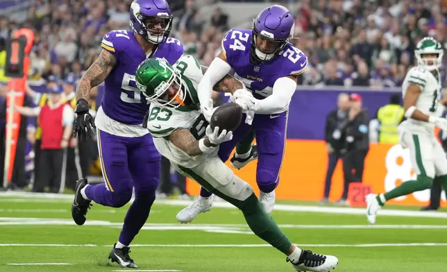 Minnesota Vikings' Camryn Bynum (24), right, fights for the ball with New York Jets' Tyler Conklin (83), center, during the second half of an NFL football game, Sunday, Oct. 6, 2024, at the Tottenham Hotspur stadium in London. (AP Photo/Kirsty Wigglesworth)