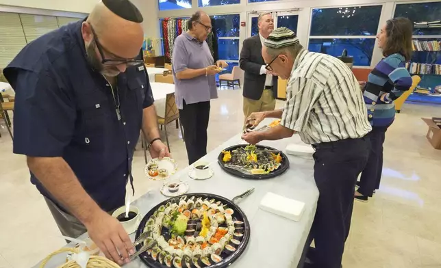 Worshipers dine on sushi after a Shabbat service, Friday, Sept. 27, 2024, at Temple Beth Sholom in Miami Beach, Fla. (AP Photo/Wilfredo Lee)