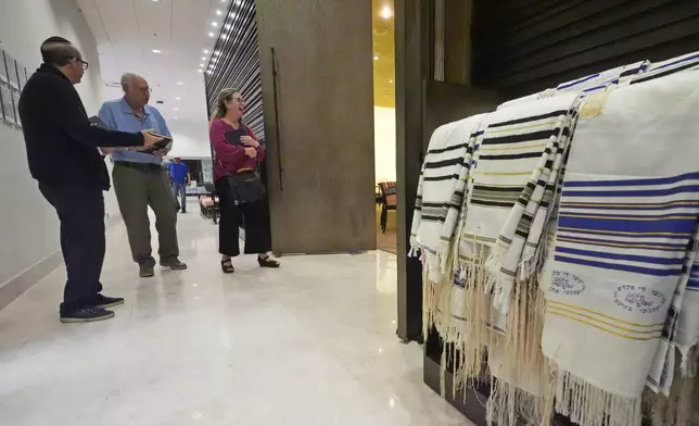 Craig Berko, left, director of membership at Temple Beth Sholom, hands out prayer books as people arrive to a Shabbat service, Friday, Sept. 27, 2024, in Miami Beach, Fla. (AP Photo/Wilfredo Lee)