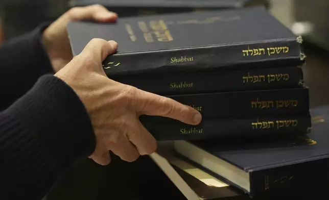 Craig Berko, director of membership at Temple Beth Sholom, prepares to hand out prayer books during a Shabbat service, Friday, Sept. 27, 2024, in Miami Beach, Fla. (AP Photo/Wilfredo Lee)