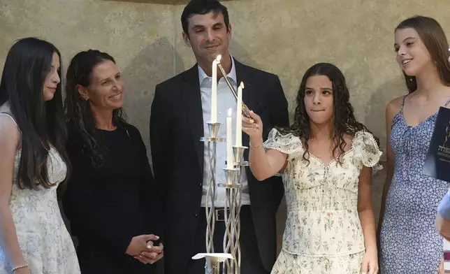 Quinn Schimel, second from left, lights a Shabbat candle as she stands with her family during a Shabbat service, Friday, Sept. 27, 2024, at Temple Beth Sholom in Miami Beach, Fla. (AP Photo/Wilfredo Lee)