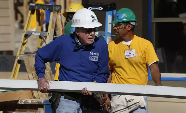 FILE - Former President Jimmy Carter helps cut wood for home construction at a Habitat for Humanity construction site in the Globeville neighborhood of Denver, Oct. 9, 2013. (AP Photo/Brennan Linsley, File)