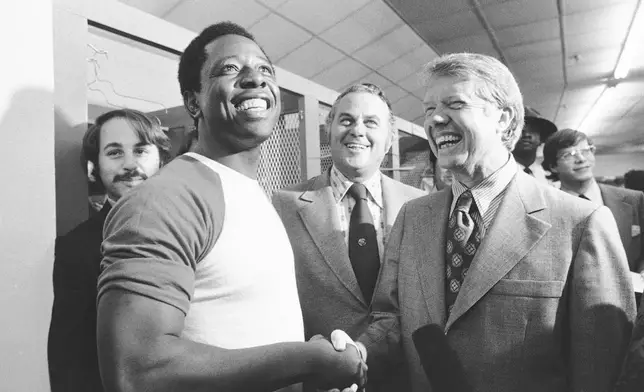 FILE - Georgia Gov. Jimmy Carter, right, and Delaware Gov. Sherman Tribbitt say hello to Atlanta Braves Hank Aaron, left, following a rain canceled game with the Los Angeles Dodgers in Atlanta, Ga., Sept. 27, 1973. (AP Photo, File)