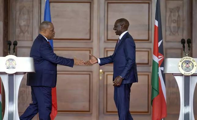 Haiti Prime Minister Garry Conille, left, and Kenya's President William Ruto, right, shake hands after a joint press conference at State House in Nairobi, Kenya, Friday, Oct. 11, 2024. (AP Photo/Brian Inganga)