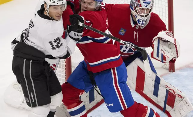 Montreal Canadiens' Jake Evans, center, tries to move Los Angeles Kings' Trevor Moore (12) from in front of Canadiens goaltender Sam Montembeault (35) during second-period NHL hockey game action Thursday, Oct. 17, 2024, in Montreal. (Ryan Remiorz/The Canadian Press via AP)