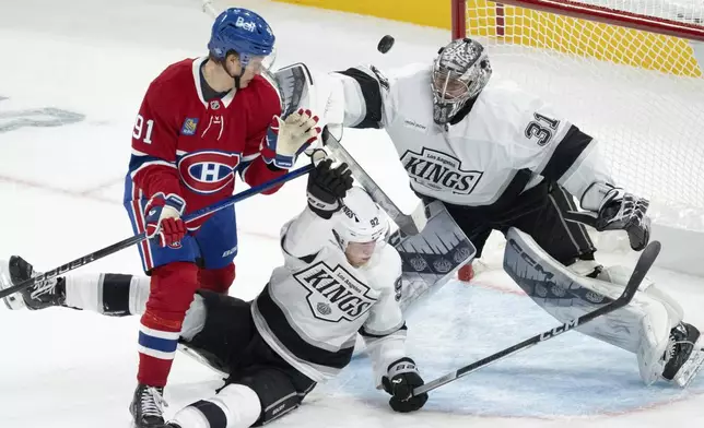 Montreal Canadiens' Oliver Kapanen (91) knocks down Los Angeles Kings' Brandt Clarke (92) as Kings goaltender David Rittich (31) makes a save during second-period NHL hockey game action Thursday, Oct. 17, 2024, in Montreal. (Ryan Remiorz/The Canadian Press via AP)