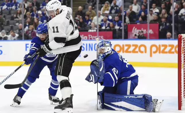 Toronto Maple Leafs' goaltender Anthony Stolarz (41) makes a save as Los Angeles Kings' Anze Kopitar (11) battles with Maple Leafs' Timothy Liljegren (37) during the third period of an NHL hockey game in Toronto, Wednesday, Oct. 16, 2024. (Frank Gunn/The Canadian Press via AP)