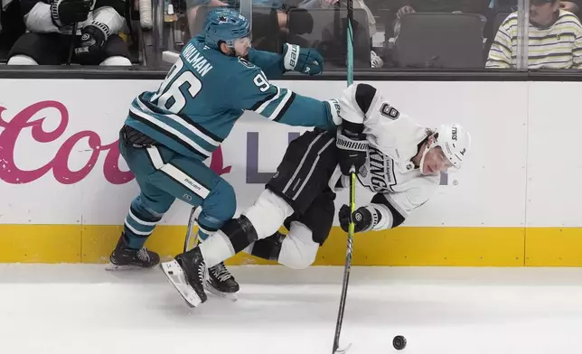 Los Angeles Kings right wing Adrian Kempe, right, is knocked to the ice by San Jose Sharks defenseman Jake Walman (96) during the third period of an NHL hockey game in San Jose, Calif., Tuesday, Oct. 29, 2024. (AP Photo/Jeff Chiu)