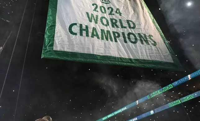 Boston Celtics general manager Brad Stevens, left, looks on as the 2024 World Championship banner is raised prior to an NBA basketball game against the New York Knicks, Tuesday, Oct. 22, 2024, in Boston. (AP Photo/Charles Krupa)