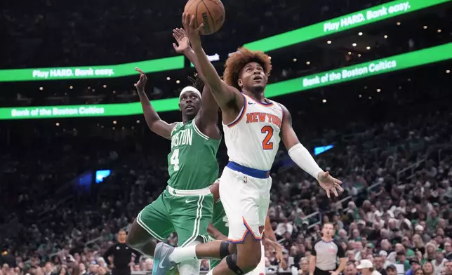 New York Knicks guard Miles McBride (2) drives to the basket past Boston Celtics guard Jrue Holiday (4) during the first half of an NBA basketball game, Tuesday, Oct. 22, 2024, in Boston. (AP Photo/Charles Krupa)