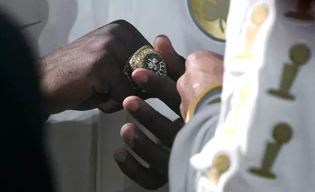 Boston Celtics guard Jaylen Brown admires his ring as the 2024 World Championship banner is raised prior to an NBA basketball game against the New York Knicks, Tuesday, Oct. 22, 2024, in Boston. (AP Photo/Charles Krupa)