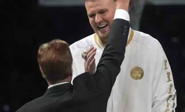 Boston Celtics center Kristaps Porzingis, celebrates with team owner Steve Pagliuca during a ceremony where the 2024 NBA Championship banner was raised prior to an NBA basketball game against the New York Knicks, Tuesday, Oct. 22, 2024, in Boston. (AP Photo/Charles Krupa)