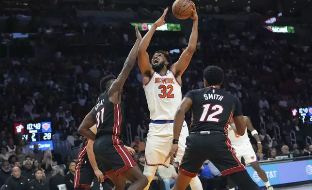 New York Knicks center Karl-Anthony Towns (32) goes to the basket as Miami Heat center Thomas Bryant (31) defends during the first half of an NBA basketball game, Wednesday, Oct. 30, 2024, in Miami. (AP Photo/Lynne Sladky)