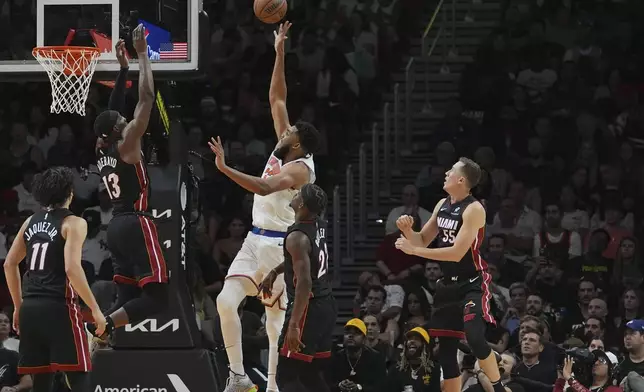 New York Knicks center Karl-Anthony Towns, center, goes to the basket as Miami Heat center Bam Adebayo (13) defends during the second half of an NBA basketball game, Wednesday, Oct. 30, 2024, in Miami. (AP Photo/Lynne Sladky)