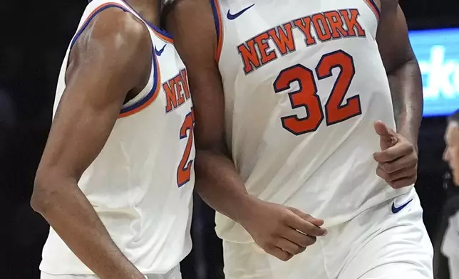 New York Knicks center Karl-Anthony Towns (32) reacts after scoring during the second half of an NBA basketball game against the Miami Heat, Wednesday, Oct. 30, 2024, in Miami. At left is New York Knicks forward Mikal Bridges, (AP Photo/Lynne Sladky)