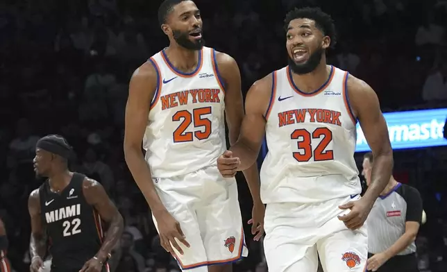 New York Knicks center Karl-Anthony Towns (32) celebrates after scoring during the second half of an NBA basketball game against the Miami Heat, Wednesday, Oct. 30, 2024, in Miami. At left is New York Knicks forward Mikal Bridges (25). (AP Photo/Lynne Sladky)